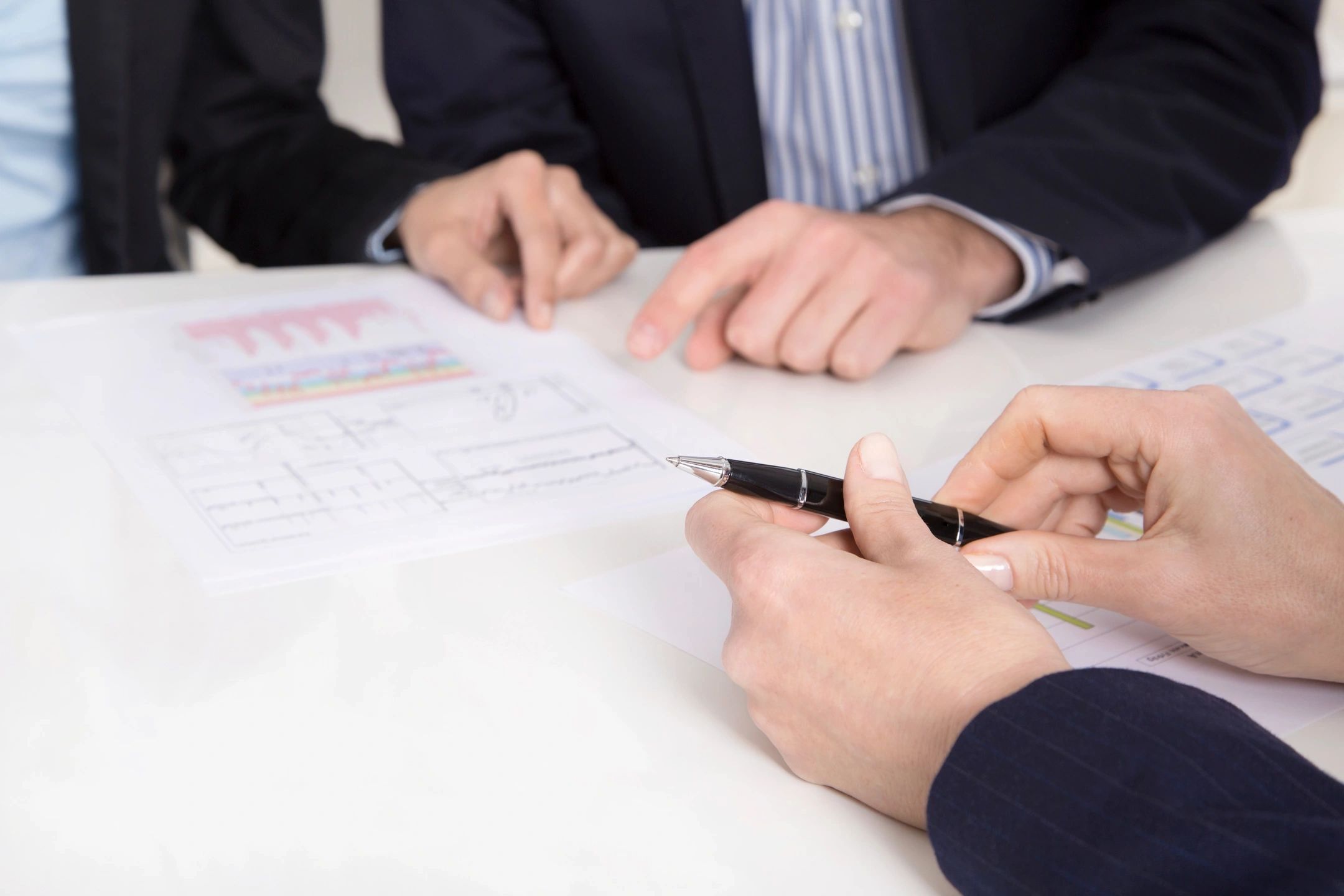 Two female accountants smiling as they consult with a male and female client in an office